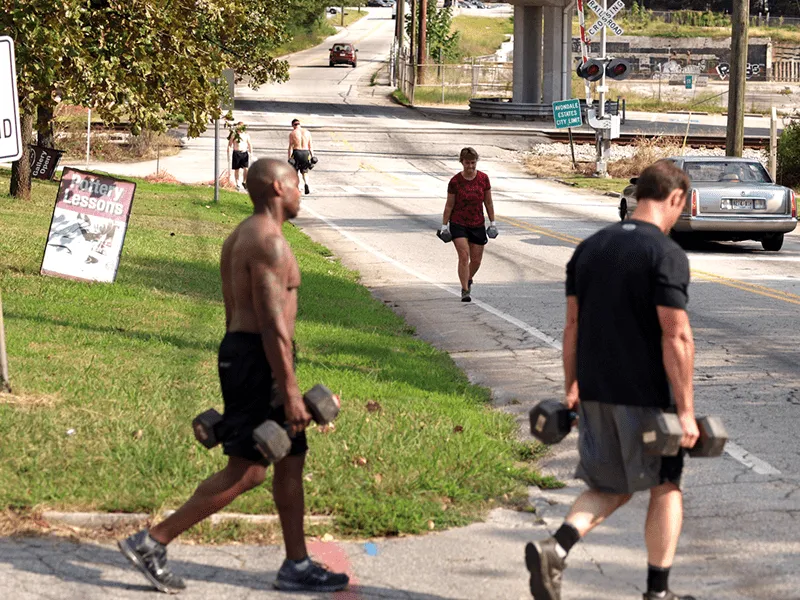 male and female crossfitters farmer's Carry exercise outside