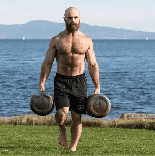 Lucas Parker Crossfit athlete farmer's carries weights outside by the sea